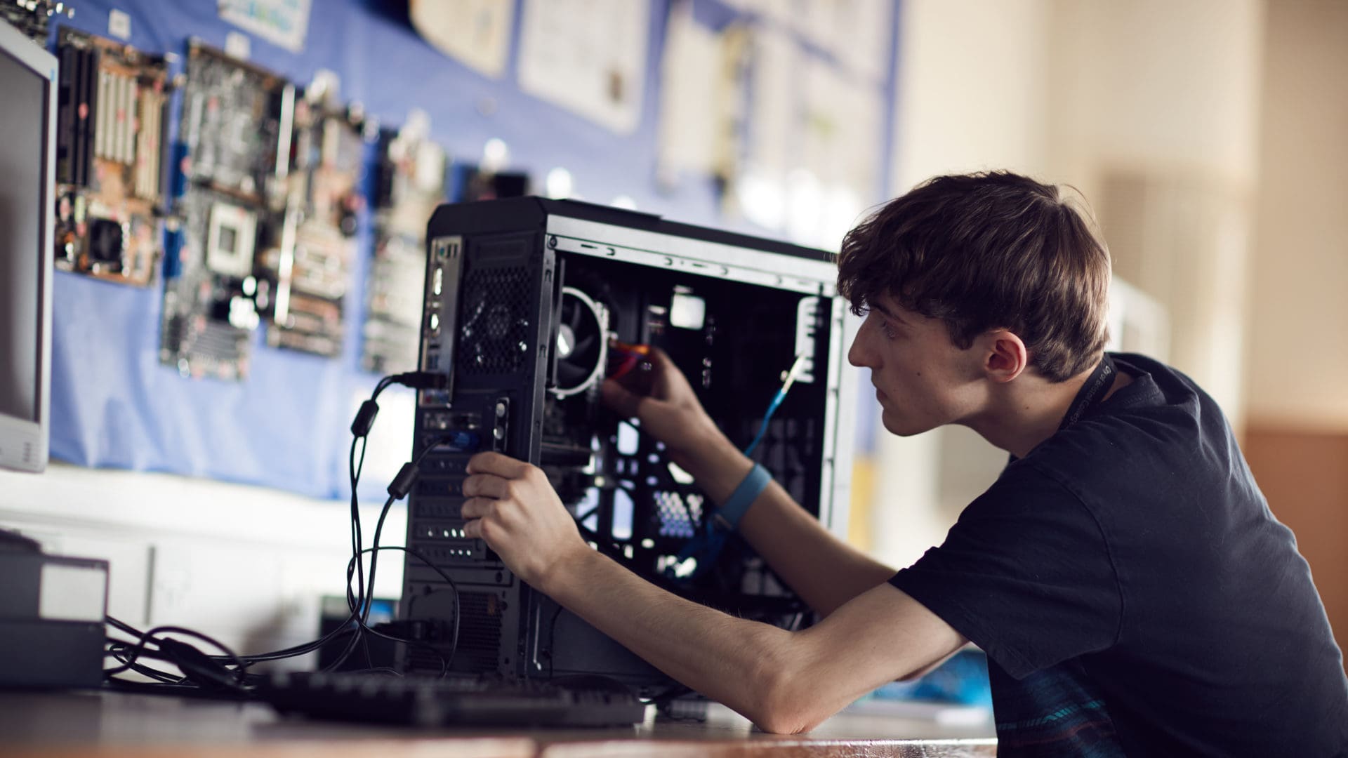  student focusing on fixing a computer on an IT course