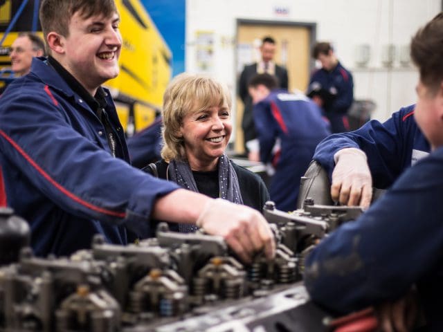 Engineering students laughing whilst fixing an engine